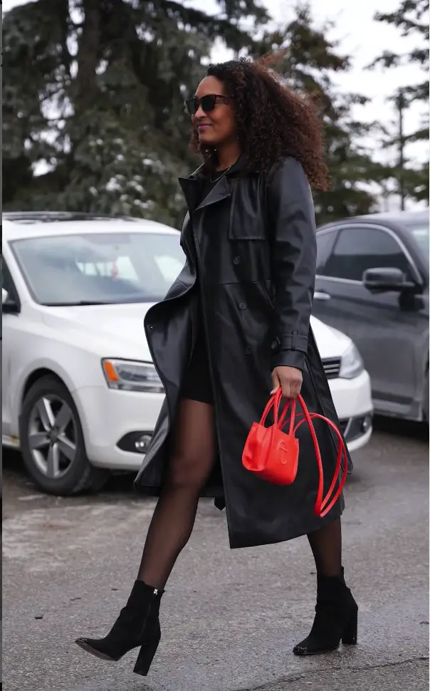 Saroya Tinker in an all black outfit with a red handbag walking to a game