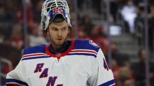 Alexandar Georgiev in a white Rangers jersey with his mask pulled up.