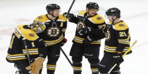 Boston Bruins' Jeremy Swayman (1), Charlie McAvoy (73), Hampus Lindholm (27) and Brandon Carlo (25) celebrate after defeating the Columbus Blue Jackets during an NHL hockey game, Saturday, Dec. 17, 2022, in Boston. (AP Photo/Michael Dwyer)