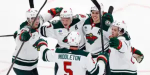 Five Wild players hug after a goal is scored.