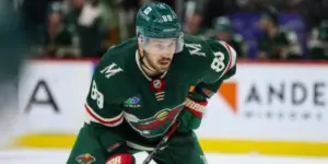 Freddy Gaudreau wears a dark green Minnesota Wild jersey while lining up for a faceoff.