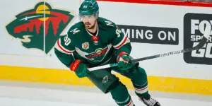 Marcus Johansson wearing green Minnesota Wild jersey while skating in a hockey game