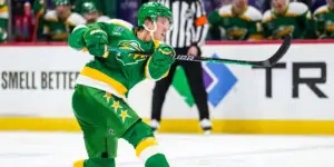 Matt Boldy wearing the third jersey of the Minnesota Wild. The jersey is bright green and yellow and is known as one of the "78s" jersey.