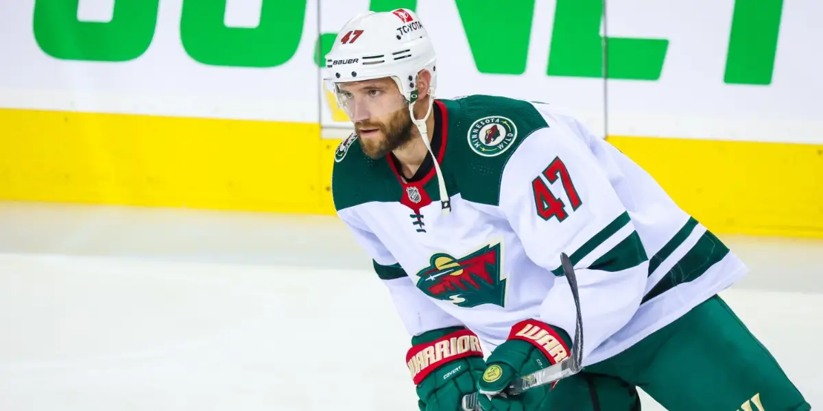 Alex Goligoski skates on the ice wearing a white Minnesota Wild jersey