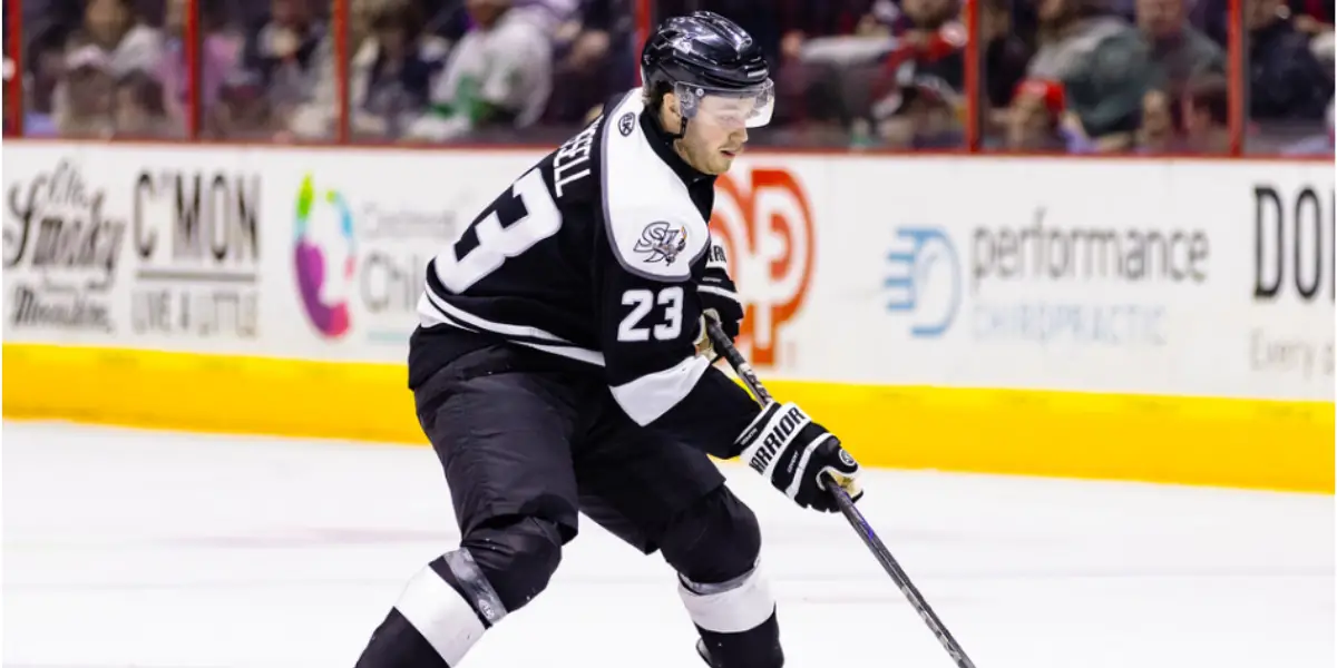 Mitchell Russell wearing black jersey while skating with the puck on his stick